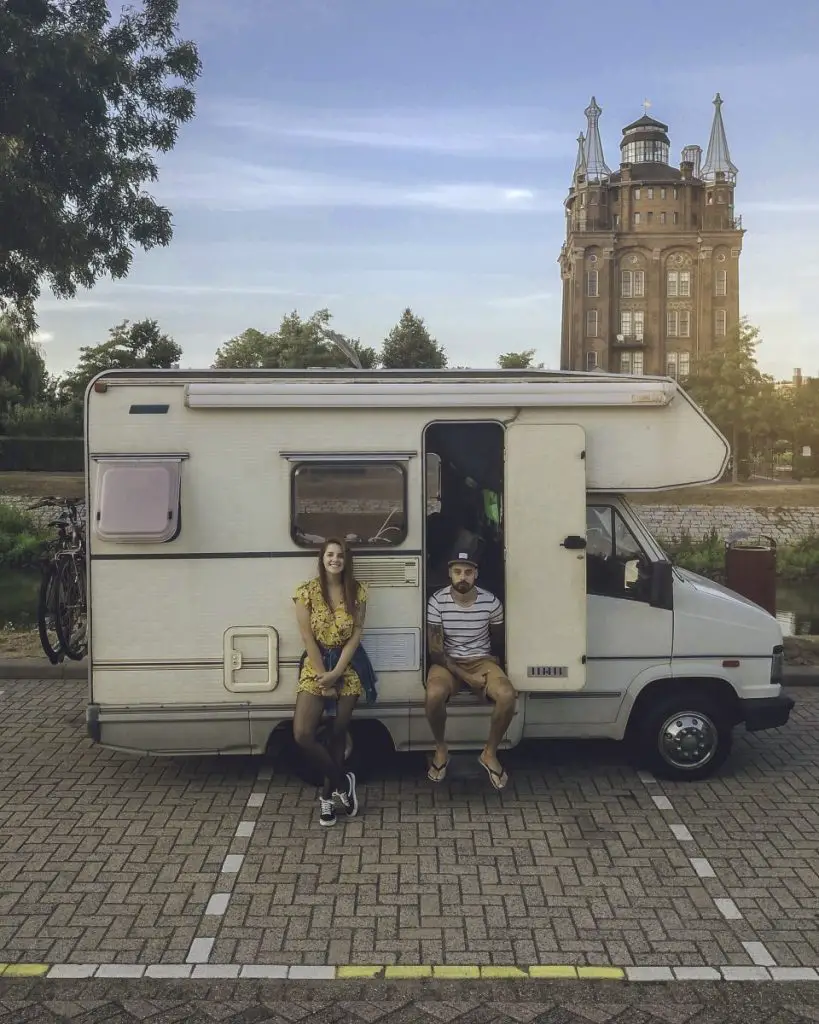 two people sit next to a class C RV