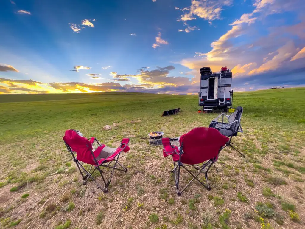 chairs next to an RV by the sunset