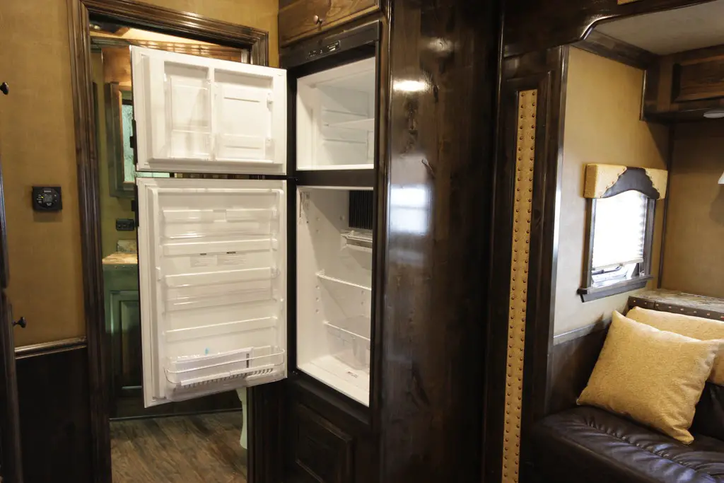 the inside of an RV with the empty refrigerator open