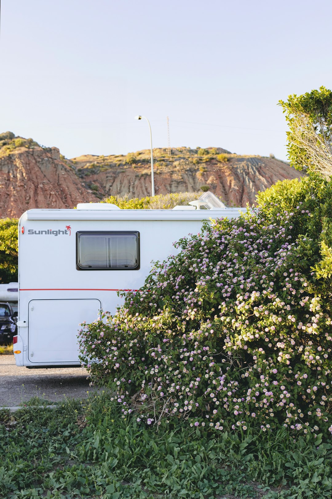 a white rv parked in a parking lot next to a bush