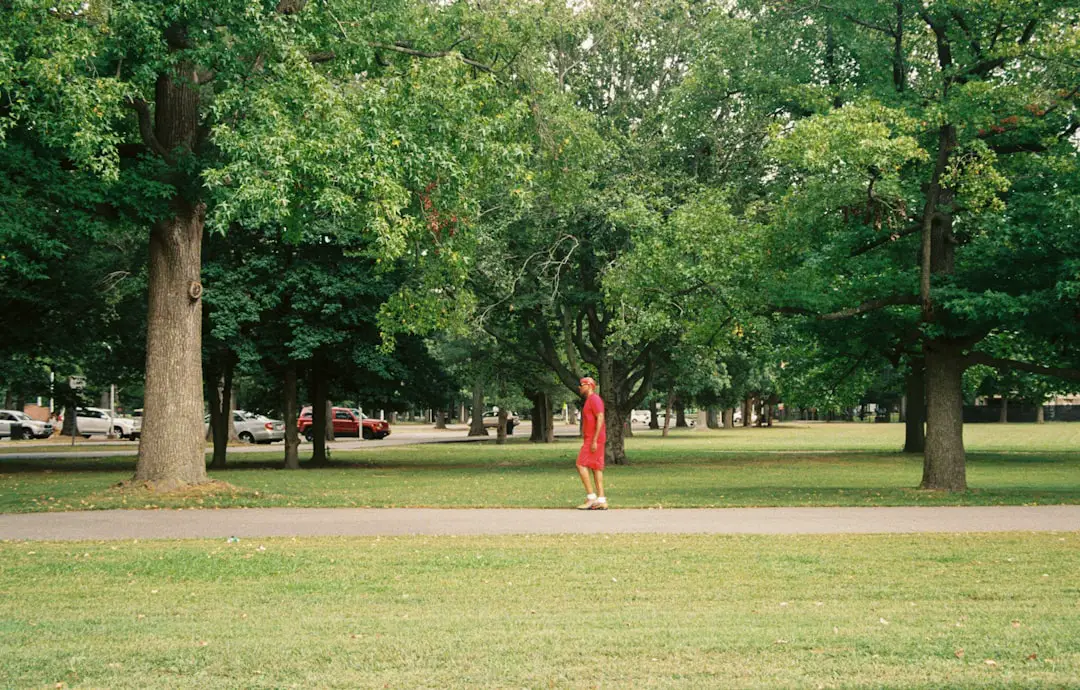a woman in a red dress walking through a park