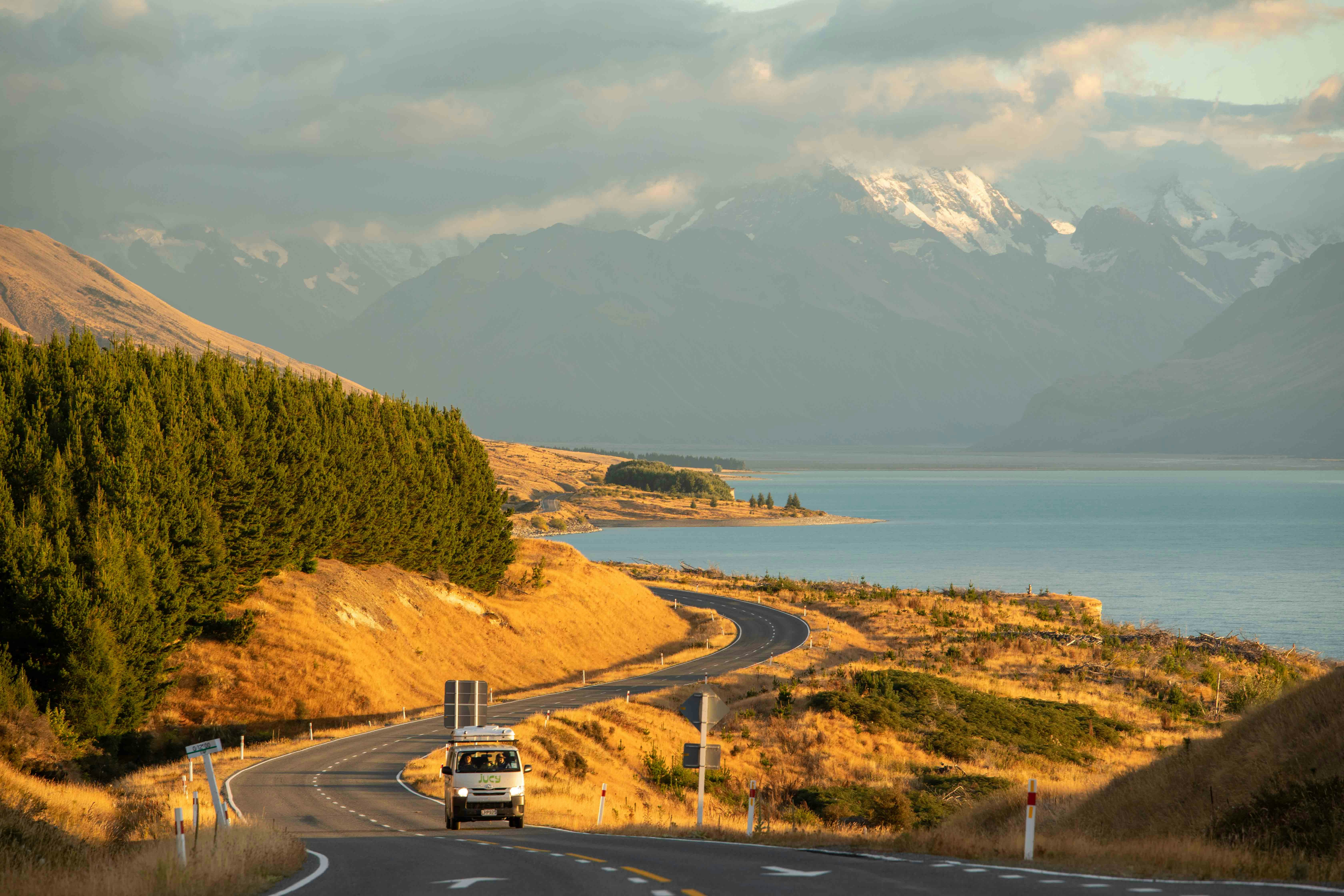a truck driving down a road next to a lake