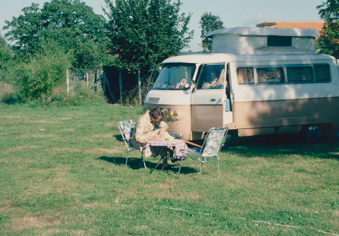 a couple of people sitting in chairs outside by a van