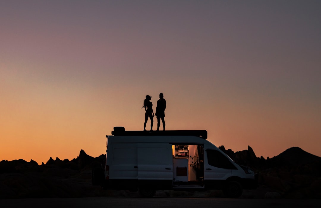 a couple of people standing on top of a van